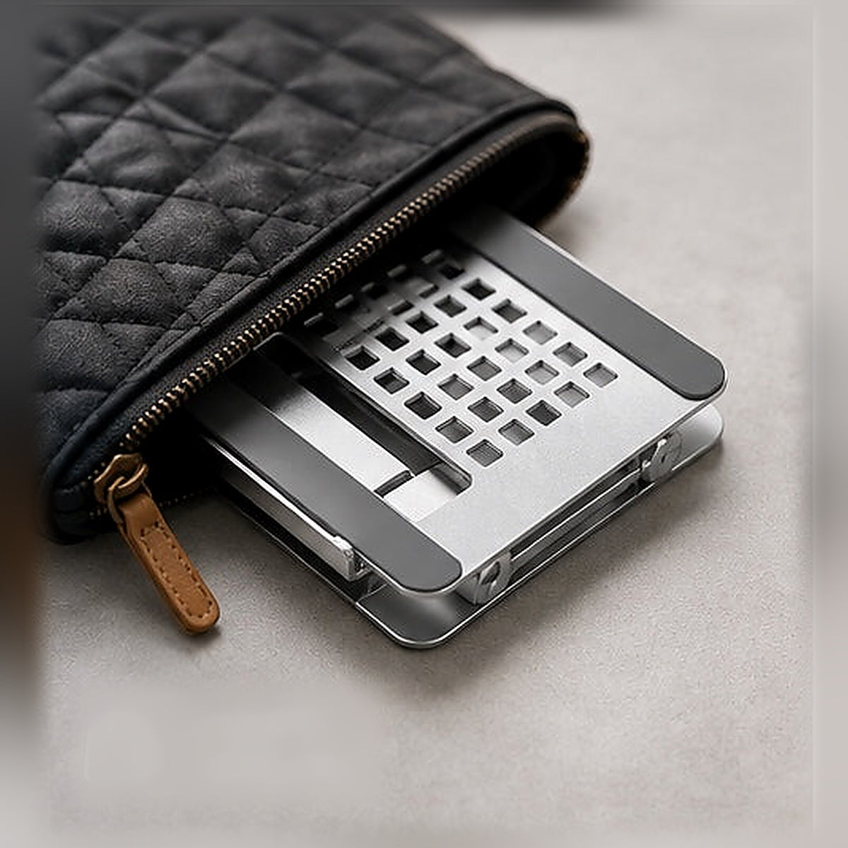 De ingeklapte MASIQ tabletstandaard schuift in een kleine tas